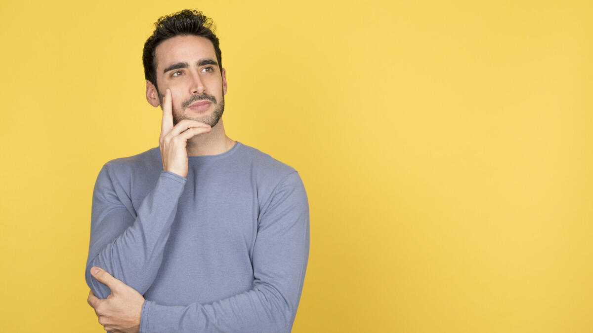 Nachdenklicher junger Mann mit einem ruhigen Gesichtsausdruck, der auf den Kopierraum blickt © Luisrojasstock / Getty Images