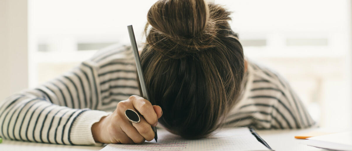 Frau liegt mit Kopf auf dem Schreibtisch.  © Westend61 / Getty Images