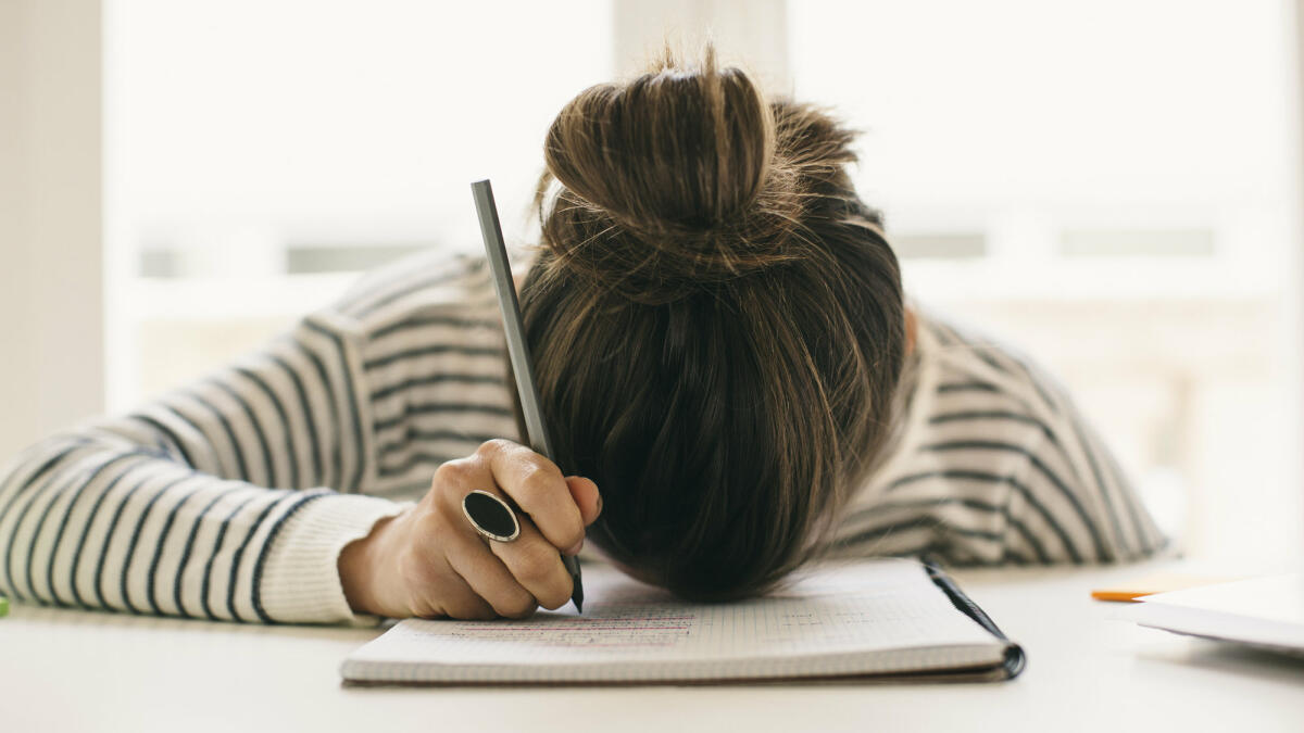 Frau liegt mit Kopf auf dem Schreibtisch.  © Westend61 / Getty Images