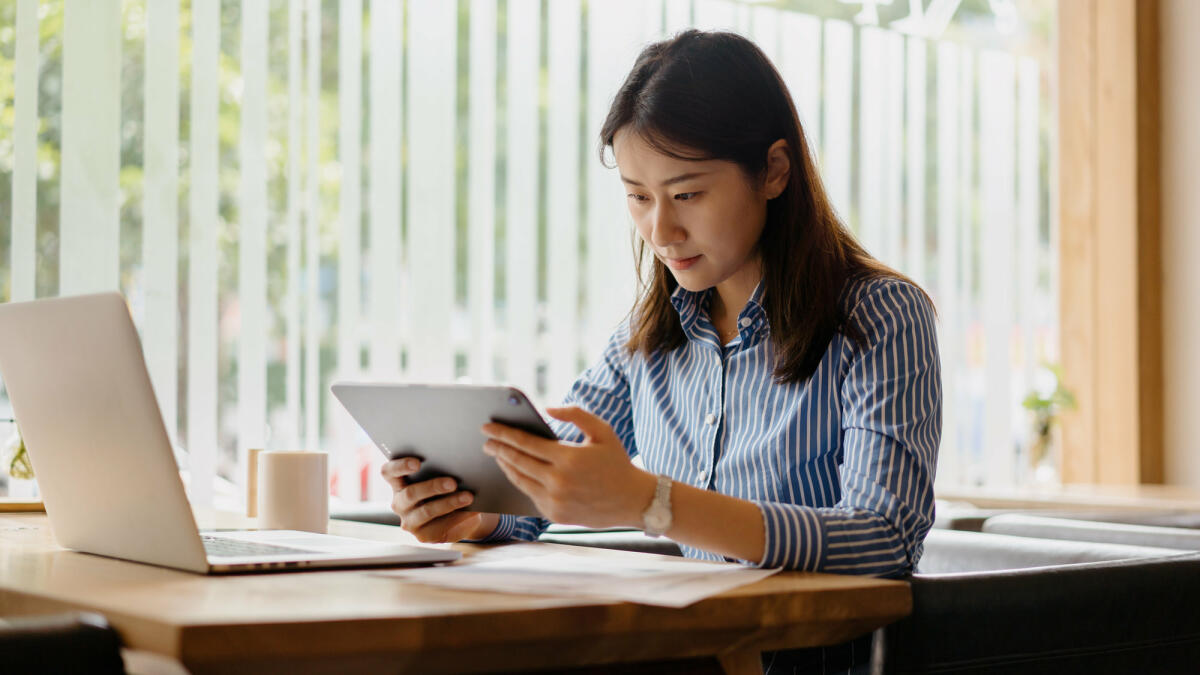 Junge Frau sitzt im Büro vor Tablet  © sinology / Getty Images