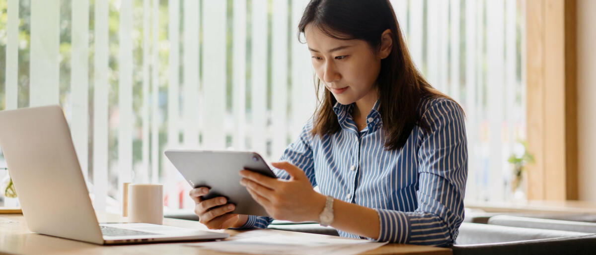 Junge Frau sitzt im Büro vor Tablet  © sinology / Getty Images