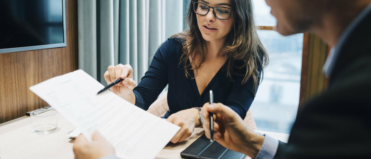 Männliche und weibliche Unternehmer besprechen während eines Treffens im Büro ein Dokument © Maskot / Getty Images