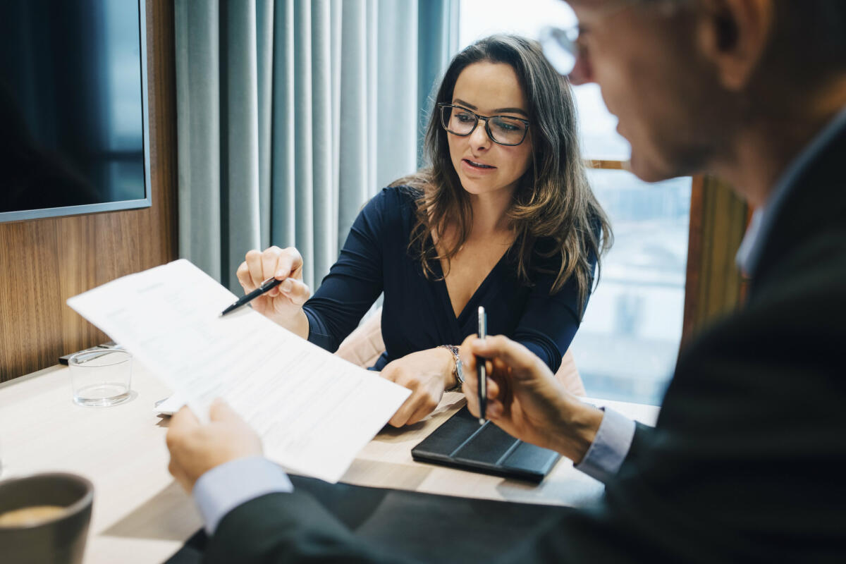 Männliche und weibliche Unternehmer besprechen während eines Treffens im Büro ein Dokument © Maskot / Getty Images