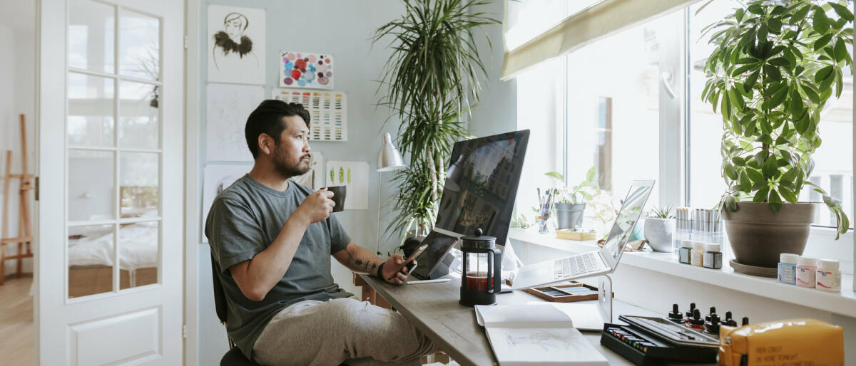 Mann mit Kaffee sitzt an Schreibtisch © visualspace / Getty Images