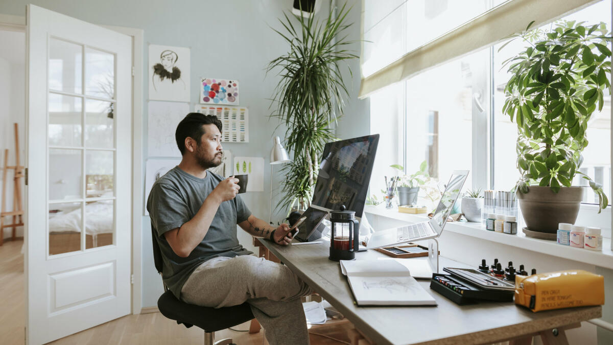 Mann mit Kaffee sitzt an Schreibtisch © visualspace / Getty Images