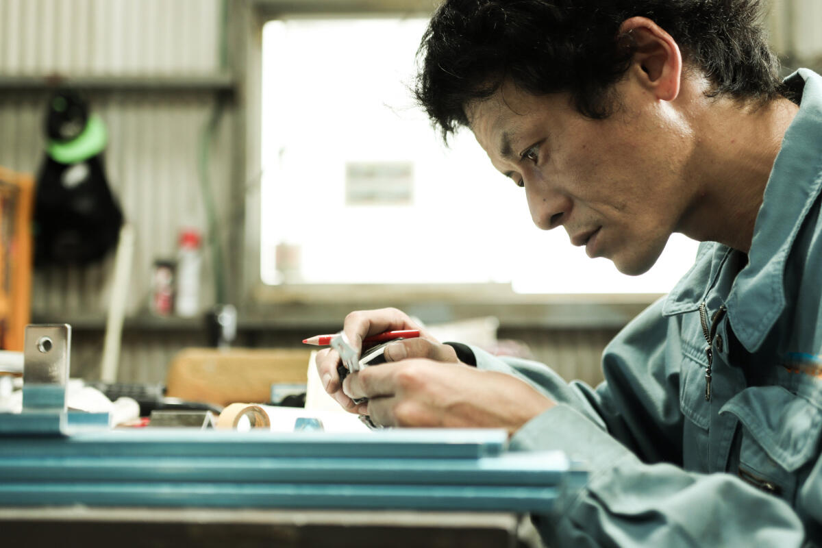 Werkstoffingenieur steht in der Fabrik und baut an einer Blaupause © kyotokushige / Getty Images