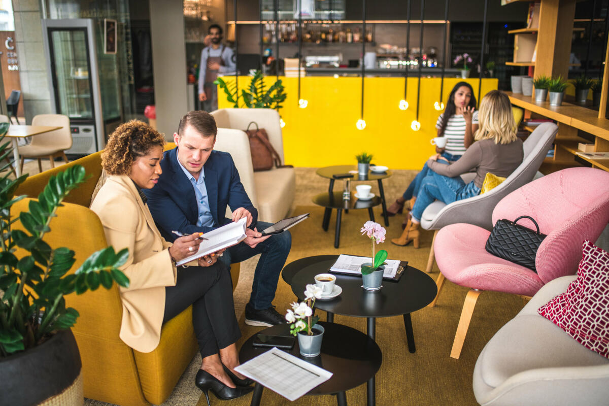 Kaukasischer Geschäftsmann Und Mid Adult Hispanische Geschäftsfrau In Einem Café © AzmanL / Getty Images