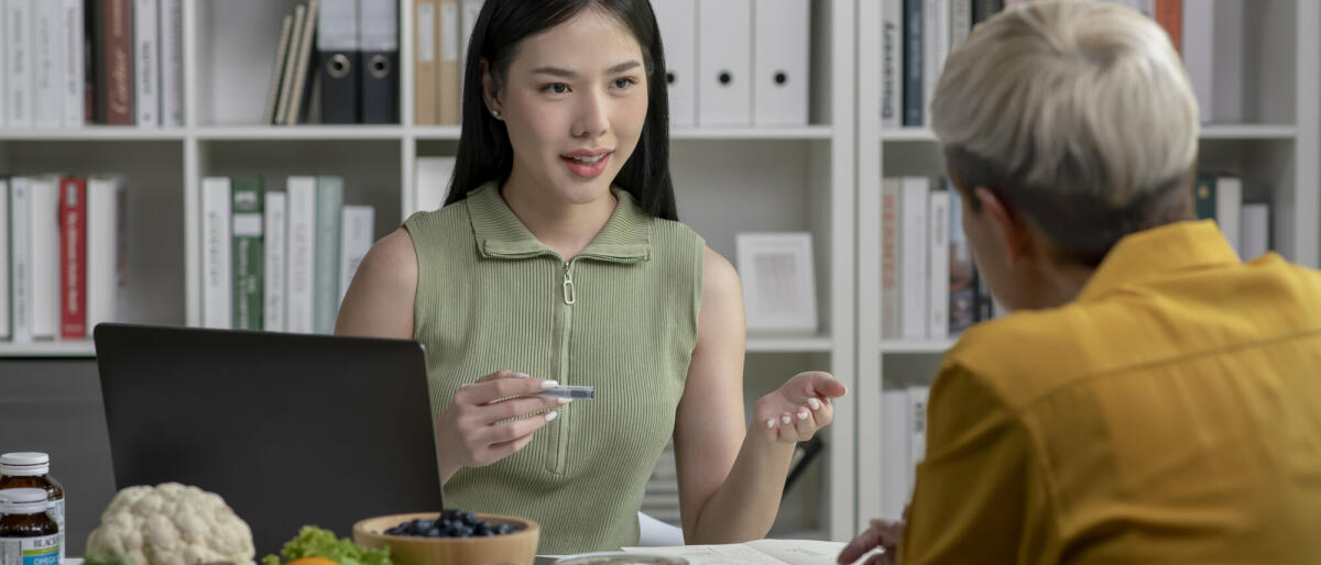 Ernährungsberaterin mit einer Kundin im Gespräch über einen Speiseplan und gesunde Produkte während einer medizinischen Beratung in der Praxis. © amenic181/ Getty Images