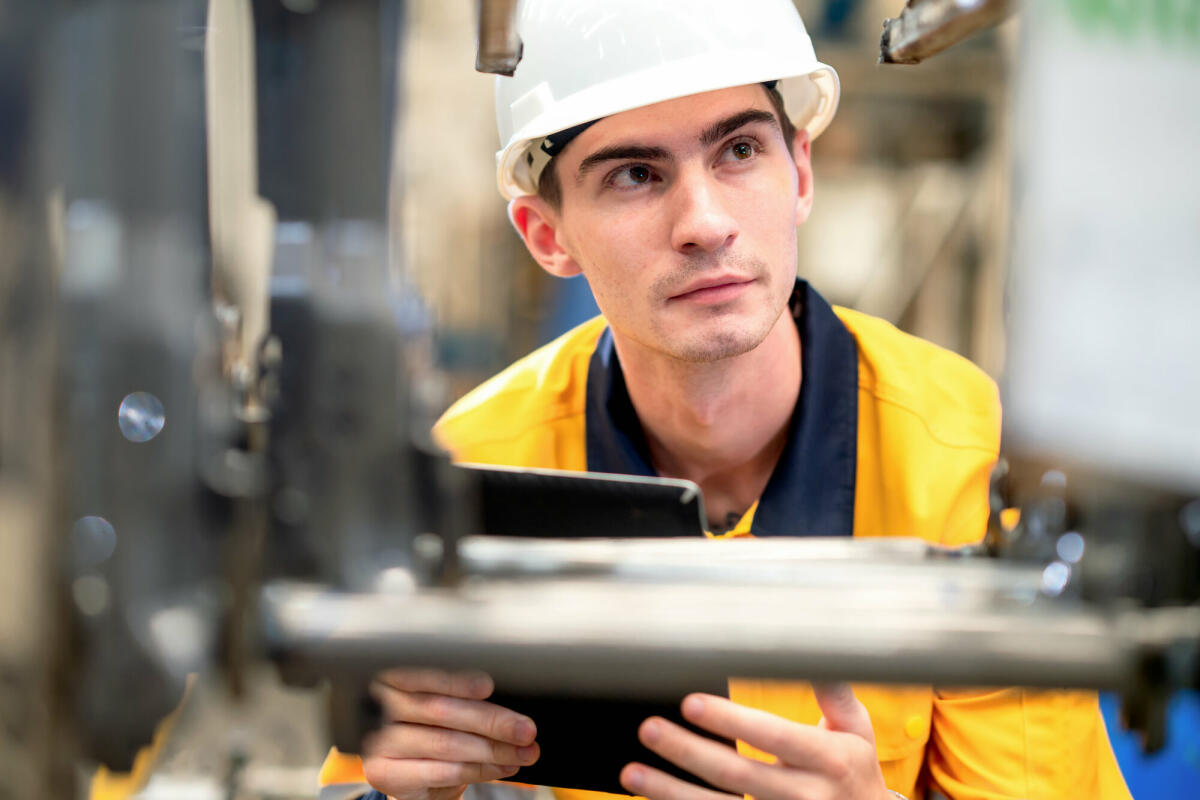 Der Prüfingenieur prüft und vergleicht die Daten der mechanischen Teile, bevor er die Teile zum Schweißen in die Robotereinheiten der Metallfabrik einlegt. © Cravetiger/ Getty Images