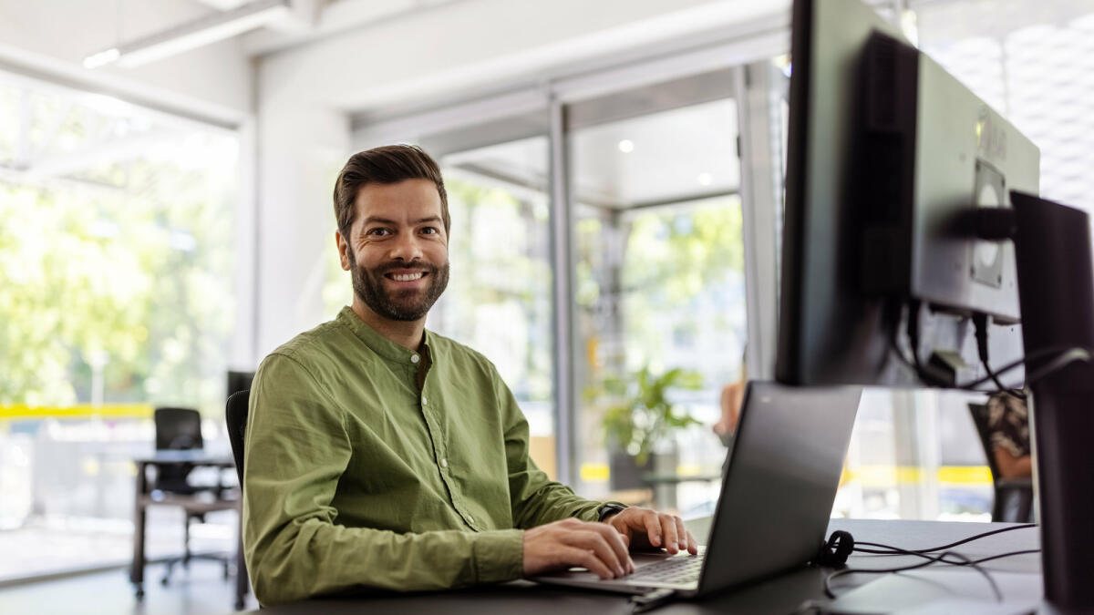 Mittlerer erwachsener Mann sitzt am Schreibtisch und arbeitet am Laptop. © Luis Alvarez / Getty Images