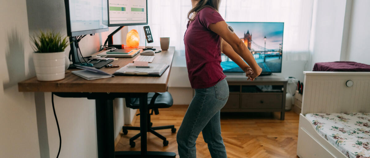 Frau im Homeoffice läuft auf dem Laufband unter dem Schreibtisch. © martin-dm / Getty Images