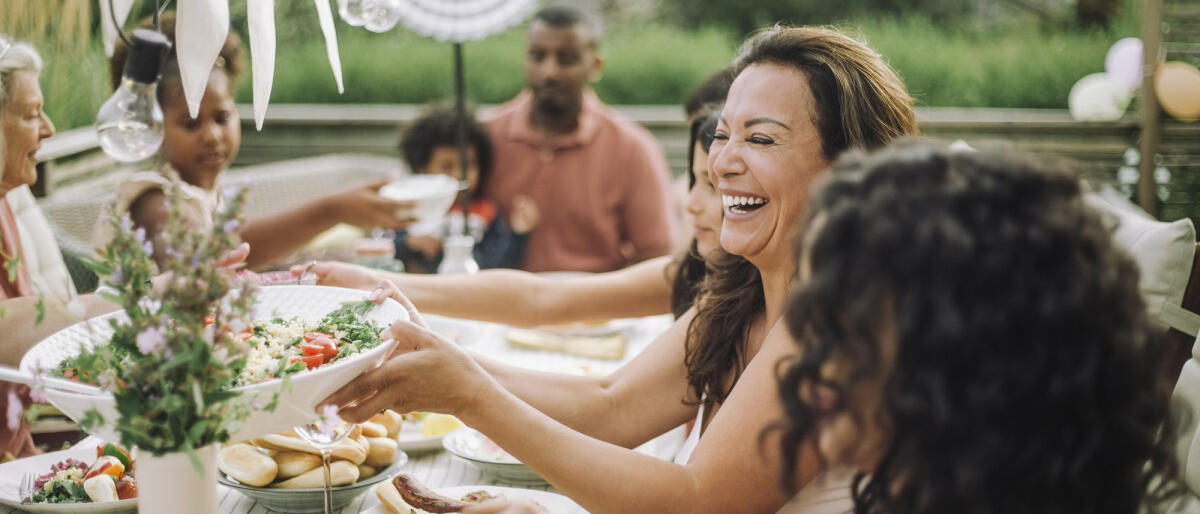 Menschen sitzen im Garten und essen zusammen © Maskot / Getty Images