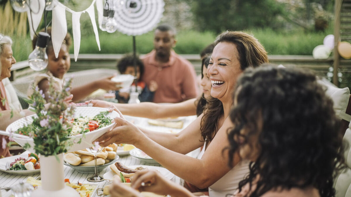 Menschen sitzen im Garten und essen zusammen © Maskot / Getty Images