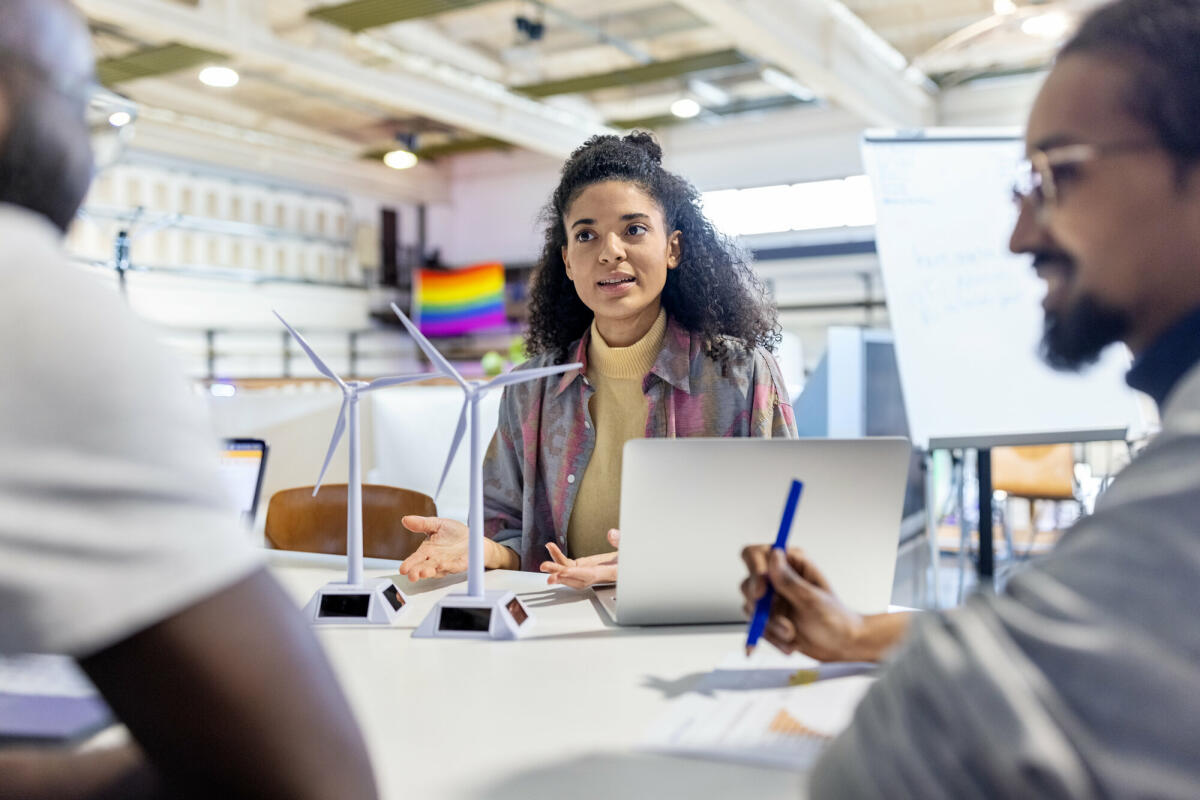 Kreative Köpfe im Coworking-Büro: Designer diskutieren mit Windkraftanlagen-Modellen. Ein Makerspace-Team arbeitet an einem erneuerbaren Energieprojekt. © alvarez/ Getty Images