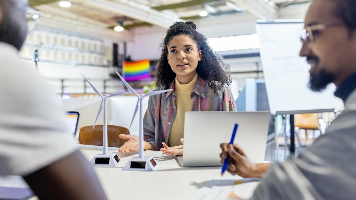 Kreative Köpfe im Coworking-Büro: Designer diskutieren mit Windkraftanlagen-Modellen. Ein Makerspace-Team arbeitet an einem erneuerbaren Energieprojekt. © alvarez/ Getty Images