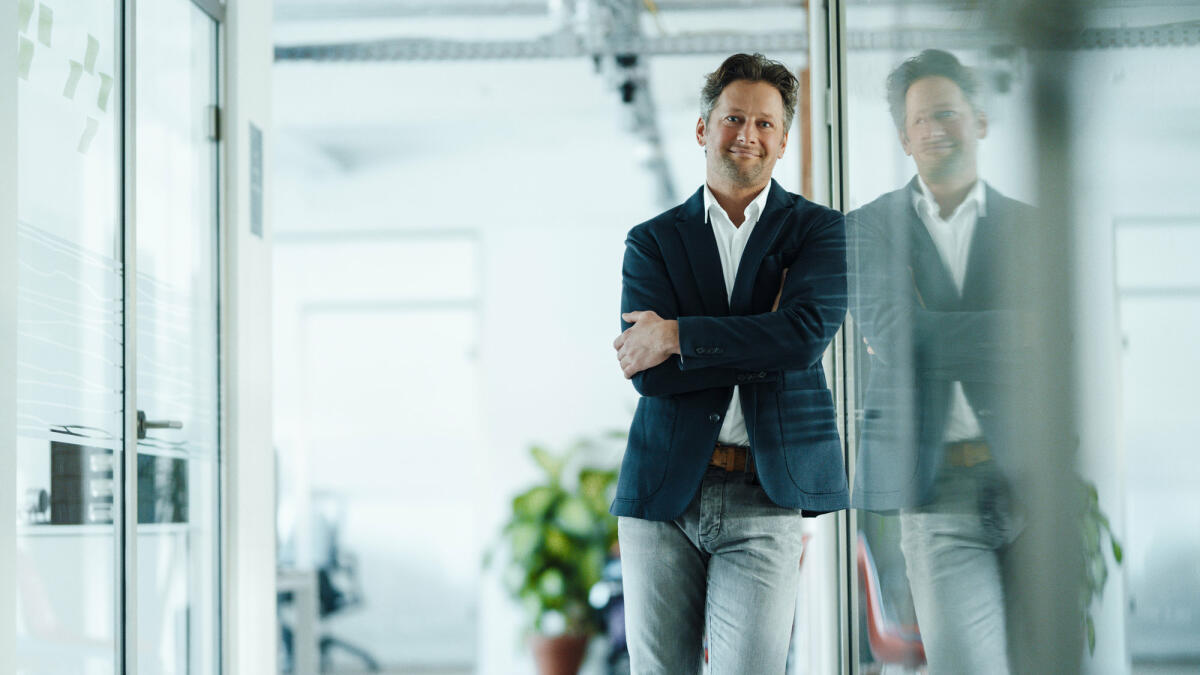 Mittelreifer Businessmann, der im Büro an einer Glasscheibe lehnt © Westend61 / Getty Images 