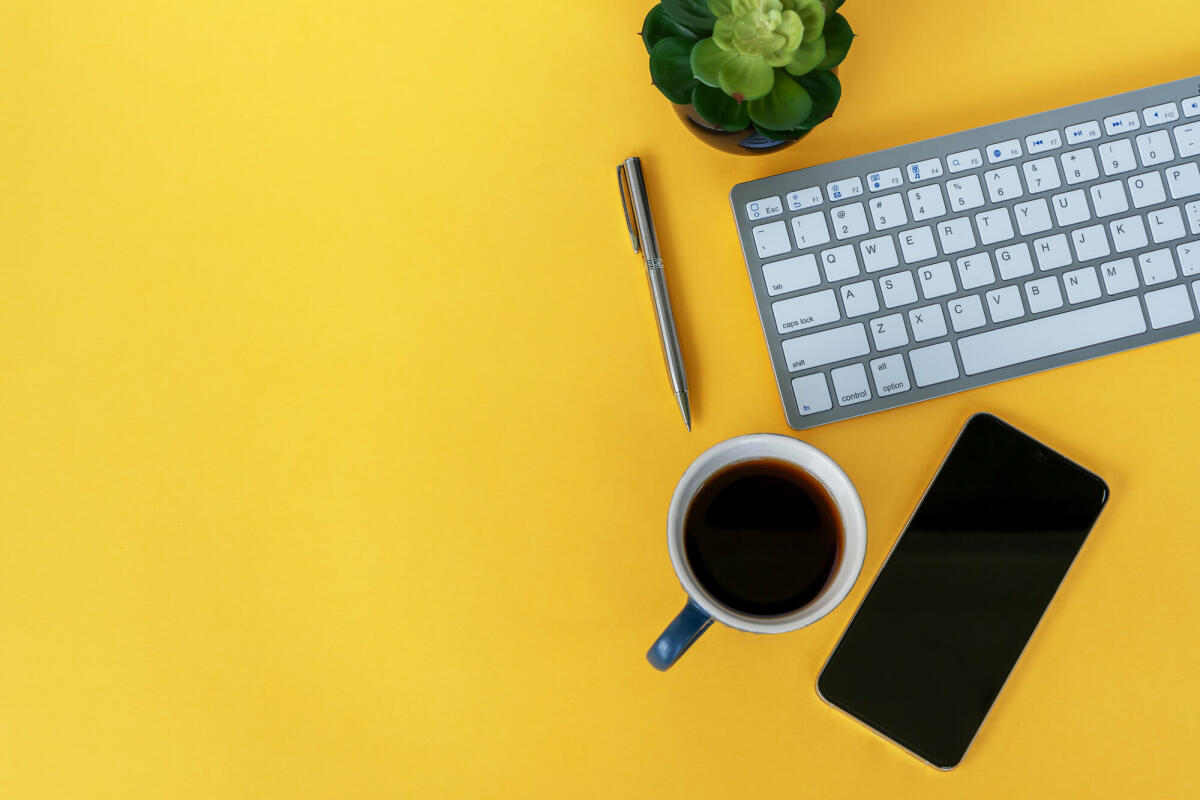 Büroschreibtisch auf gelbem Hintergrund mit Kopierraum © Nora Carol Photography / Getty Images