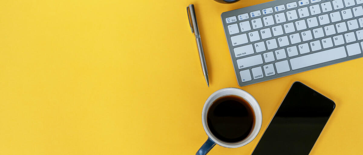 Büroschreibtisch auf gelbem Hintergrund mit Kopierraum © Nora Carol Photography / Getty Images