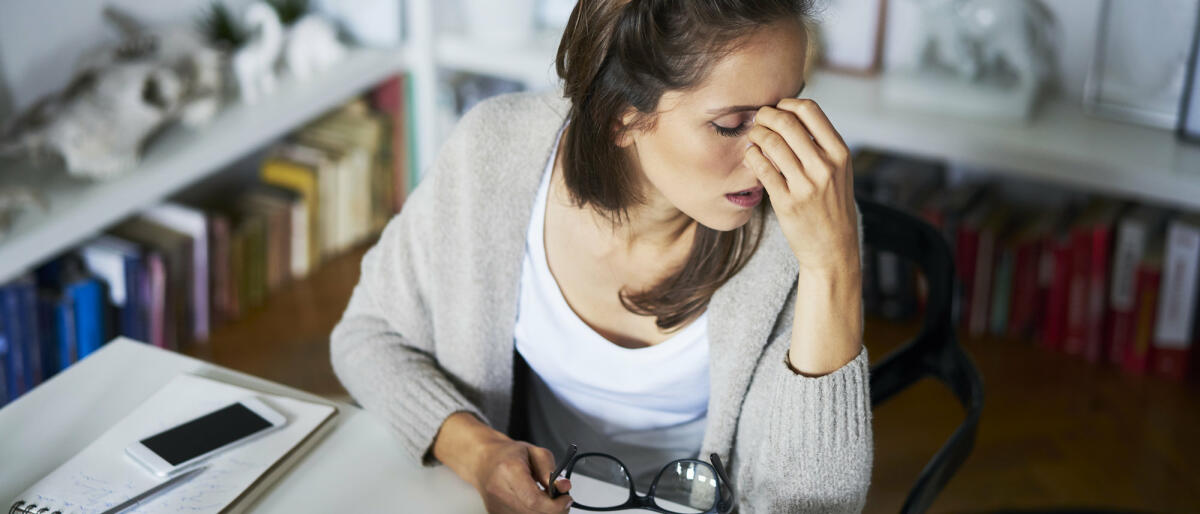 Junge Frau am Schreibtisch mit Kopfschmerzen © Westend61 / Getty Images