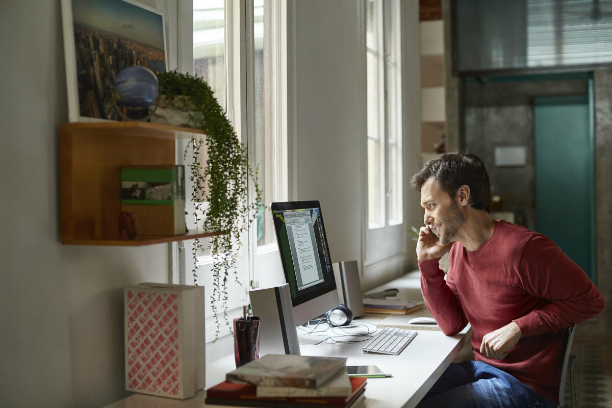 Mann sitzt am Schreibtisch im Homeoffice und telefoniert.  © Morsa Images / Getty Images