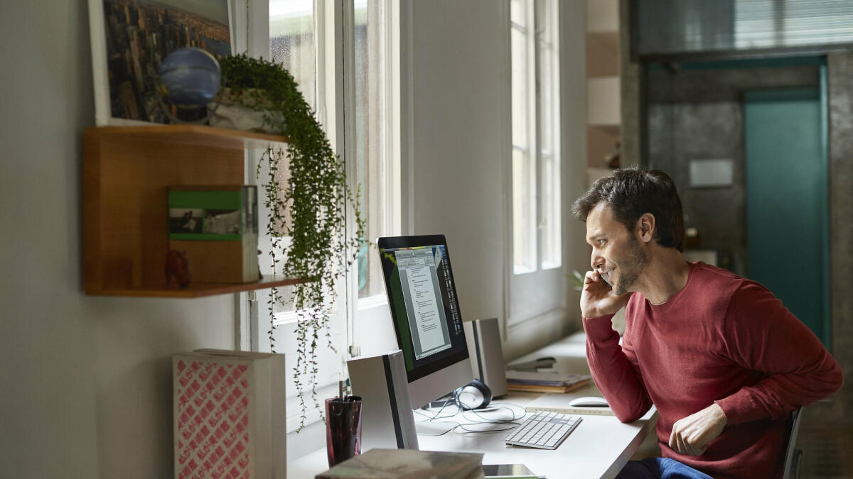 Mann sitzt am Schreibtisch im Homeoffice und telefoniert.  © Morsa Images / Getty Images