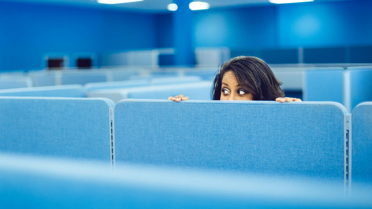 Eine Frau versteckt sich bei der Arbeit. © Getty Images / ferrantraite