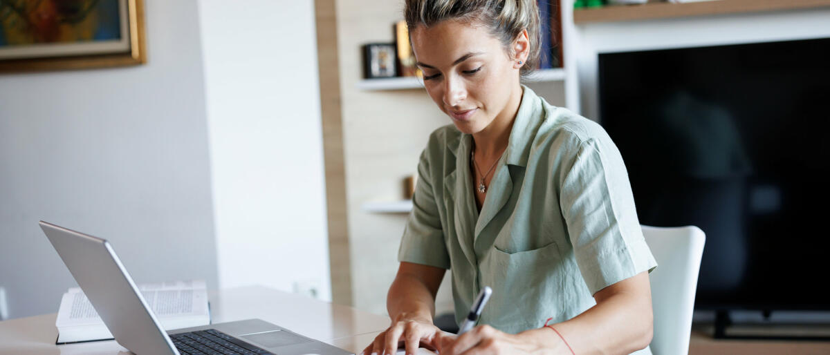 Schöne junge Frau, die sich Notizen macht, während sie von zu Hause aus lernt © bojanstory / Getty Images