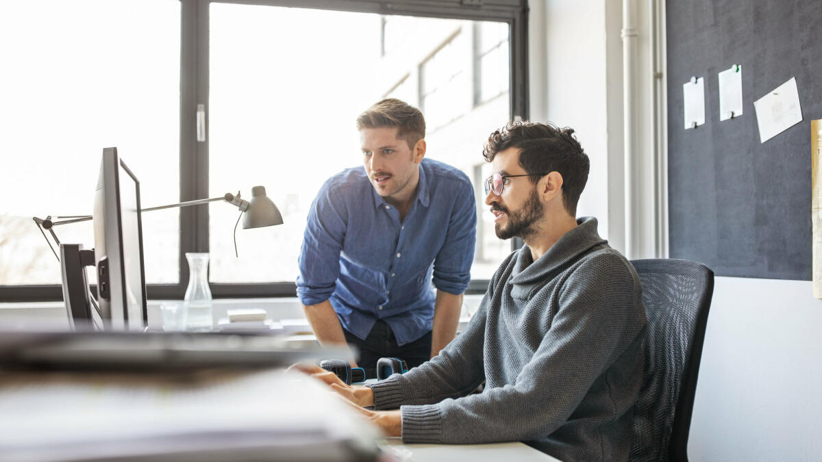 Geschäftsleute, die gemeinsam an einem Computer arbeiten © Luis Alvarez / Getty Images