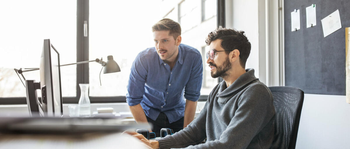 Geschäftsleute, die gemeinsam an einem Computer arbeiten © Luis Alvarez / Getty Images