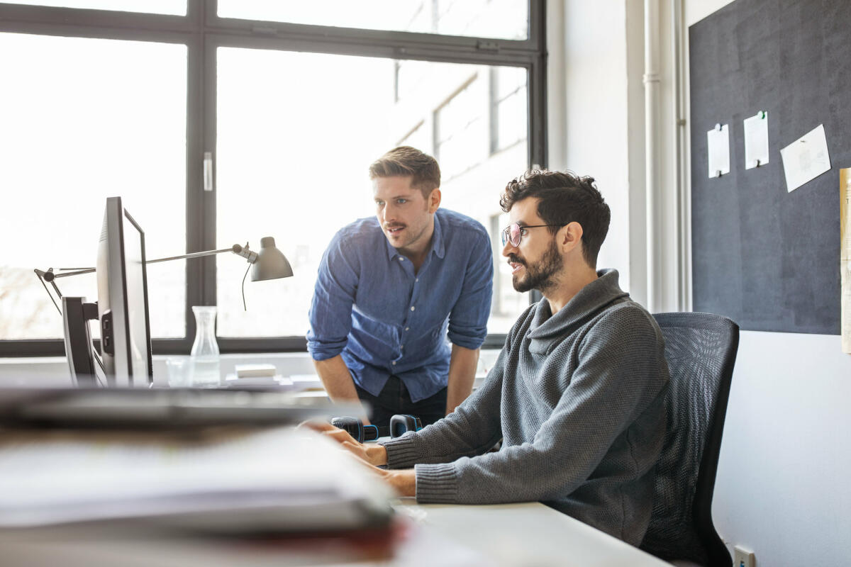 Geschäftsleute, die gemeinsam an einem Computer arbeiten © Luis Alvarez / Getty Images