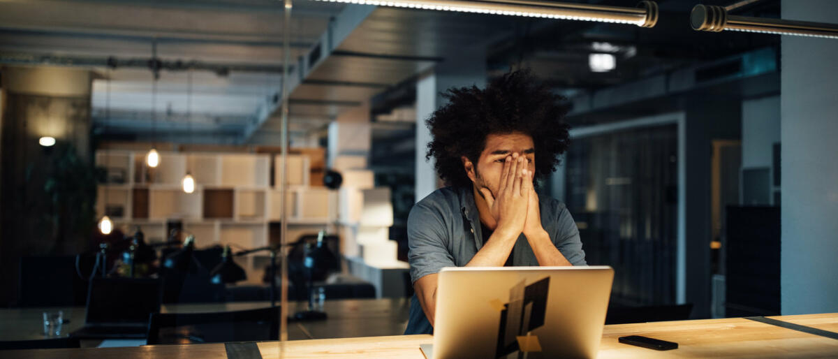 Mann sitzt mit Händen vorm Gesicht am Schreibtisch.  © Luis Alvarez / Getty Images