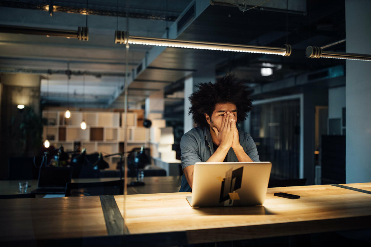 Mann sitzt mit Händen vorm Gesicht am Schreibtisch.  © Luis Alvarez / Getty Images