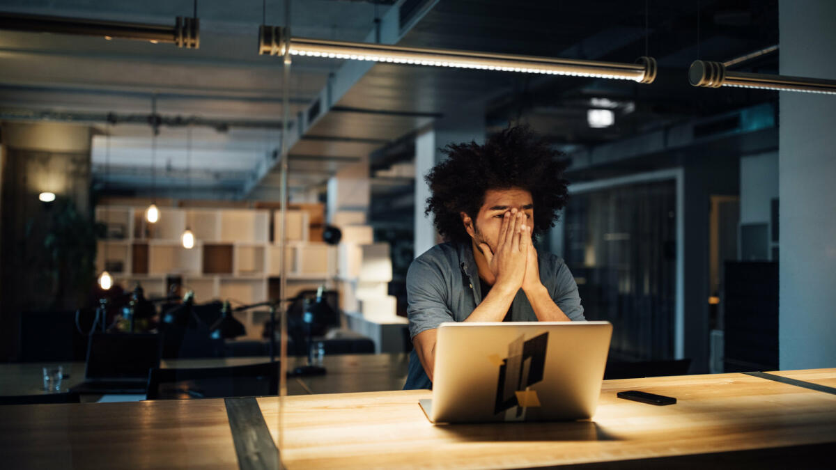 Mann sitzt mit Händen vorm Gesicht am Schreibtisch.  © Luis Alvarez / Getty Images