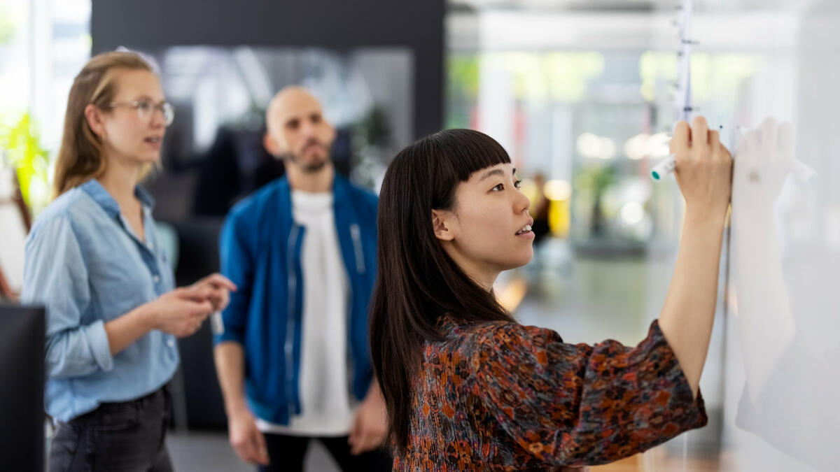 Frau steht am Whiteboard  © Luis Alvarez / Getty Images 