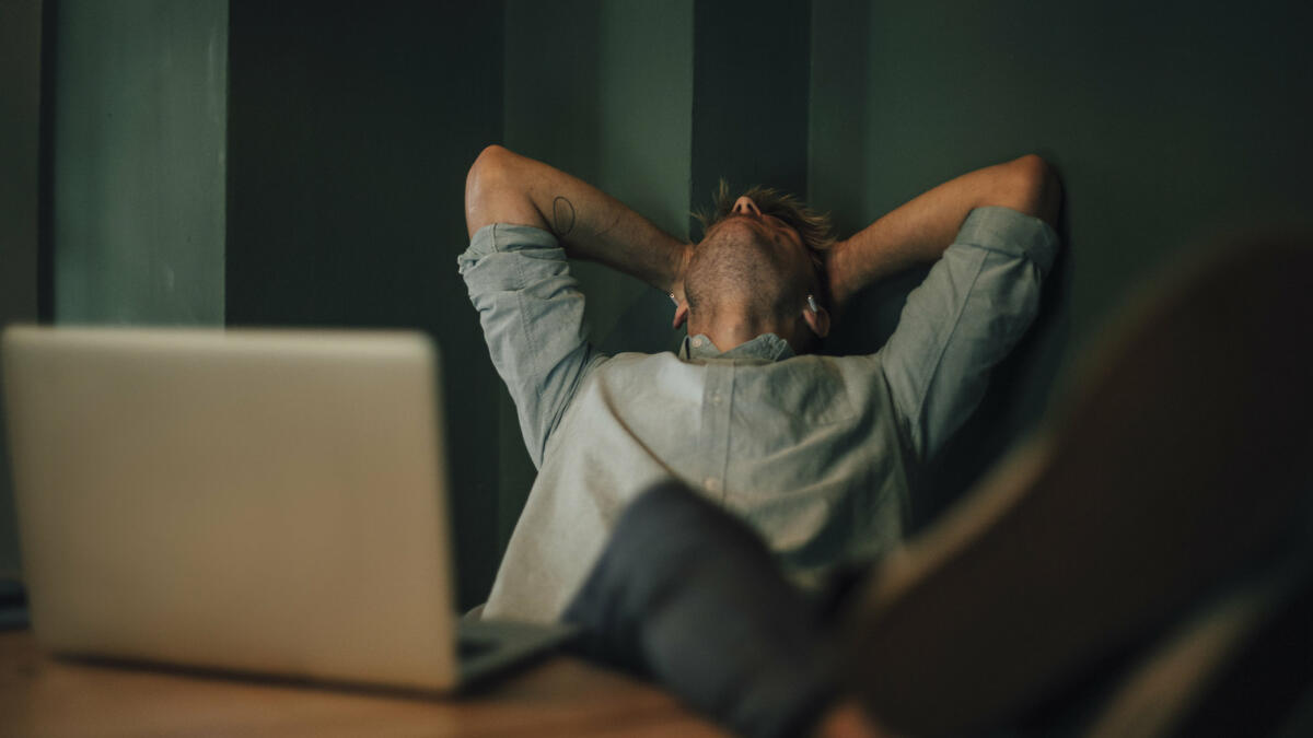 Mann lehnt sich am Schreibtisch zurück. © Westend61 / Getty Images