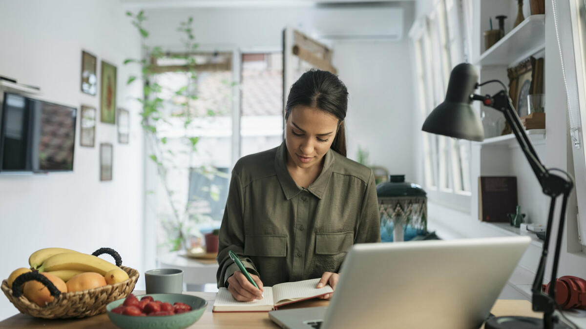 Frau sitzt am Schreibtisch und notiert sich etwas  © Brothers91 / Getty Images