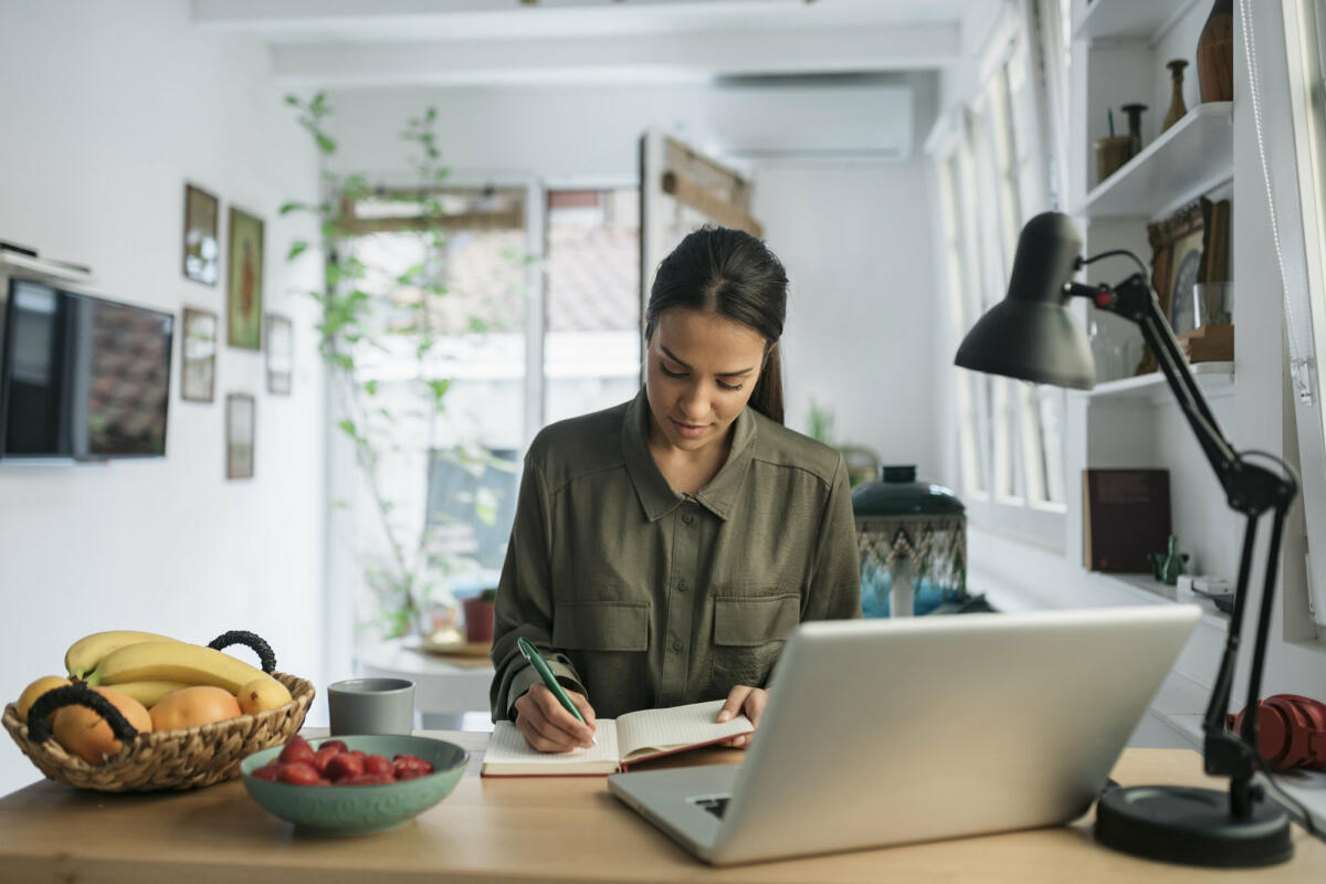 Frau sitzt am Schreibtisch und notiert sich etwas  © Brothers91 / Getty Images