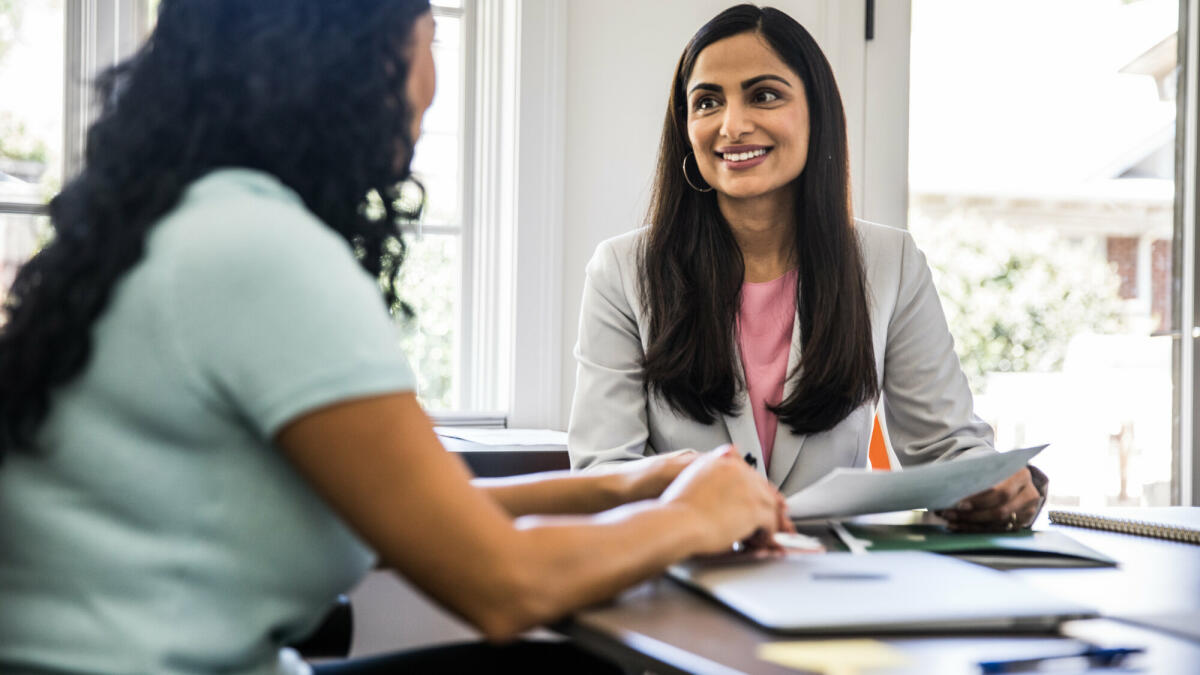 Zwei Frauen, die im Büro sind und lächeln. © MoMo Productions/ Getty Images