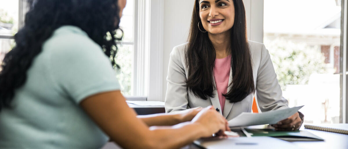 Zwei Frauen, die im Büro sind und lächeln. © MoMo Productions/ Getty Images