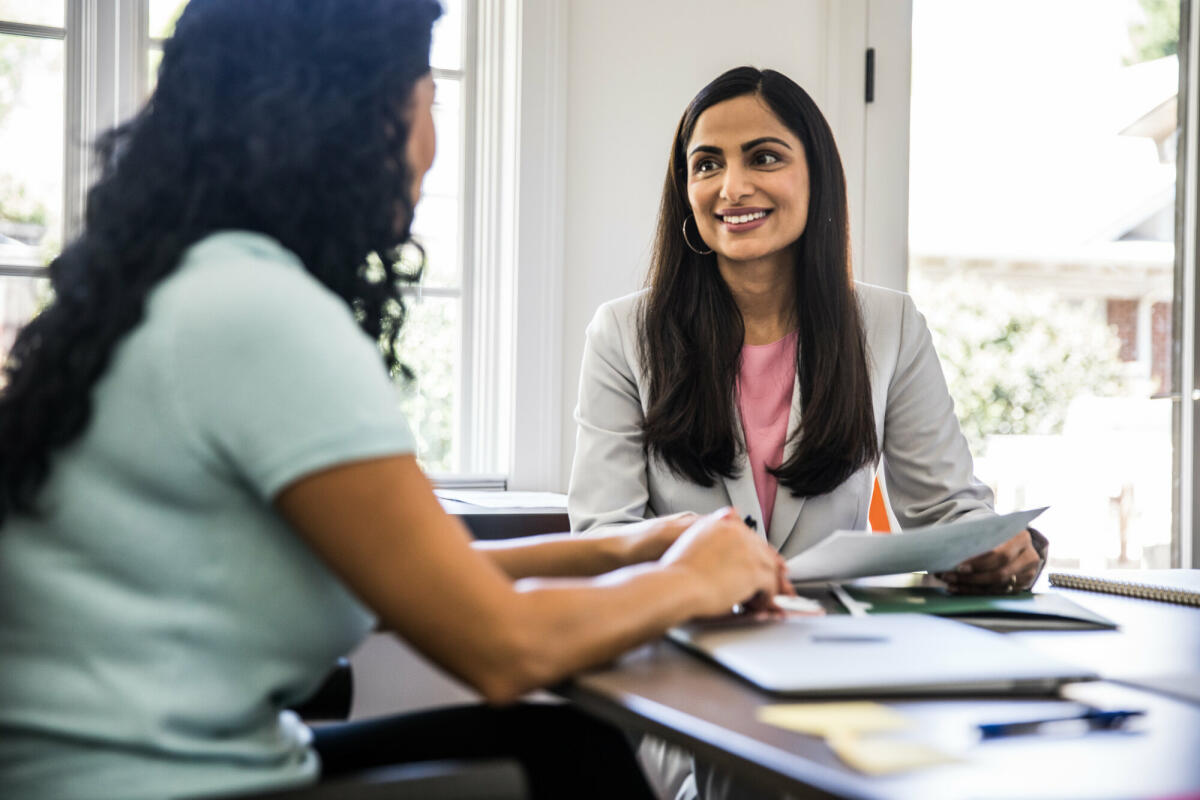 Zwei Frauen, die im Büro sind und lächeln. © MoMo Productions/ Getty Images