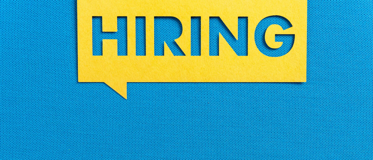 Gelbes Sprechblasenbanner "Hiring" auf leerem blau strukturiertem Hintergrund © zakokor / Getty Images