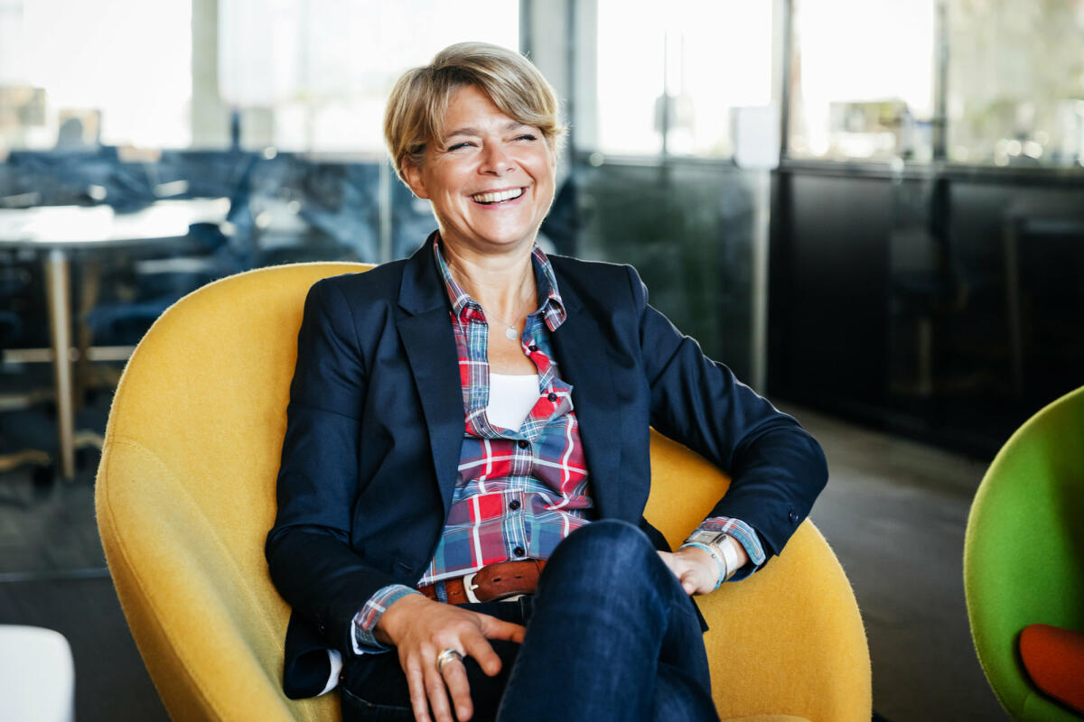 Eine Frau mittleren Alters sitzt lachend in einem gelben Sessel © Tom Werner / Getty Images