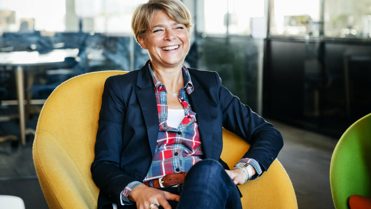 Eine Frau mittleren Alters sitzt lachend in einem gelben Sessel © Tom Werner / Getty Images