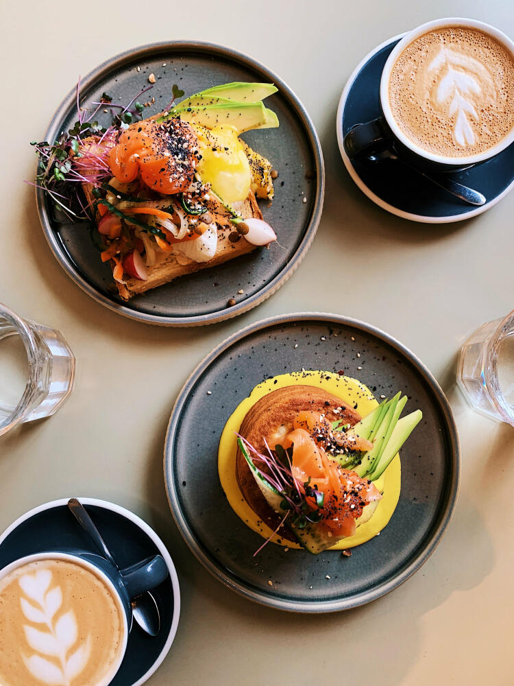 Avocado-Toast mit pochierten Eiern und Lachs und Pfannkuchen mit Avocado und Lachs, direkt von oben gesehen © Alexander Spatari / Getty Images