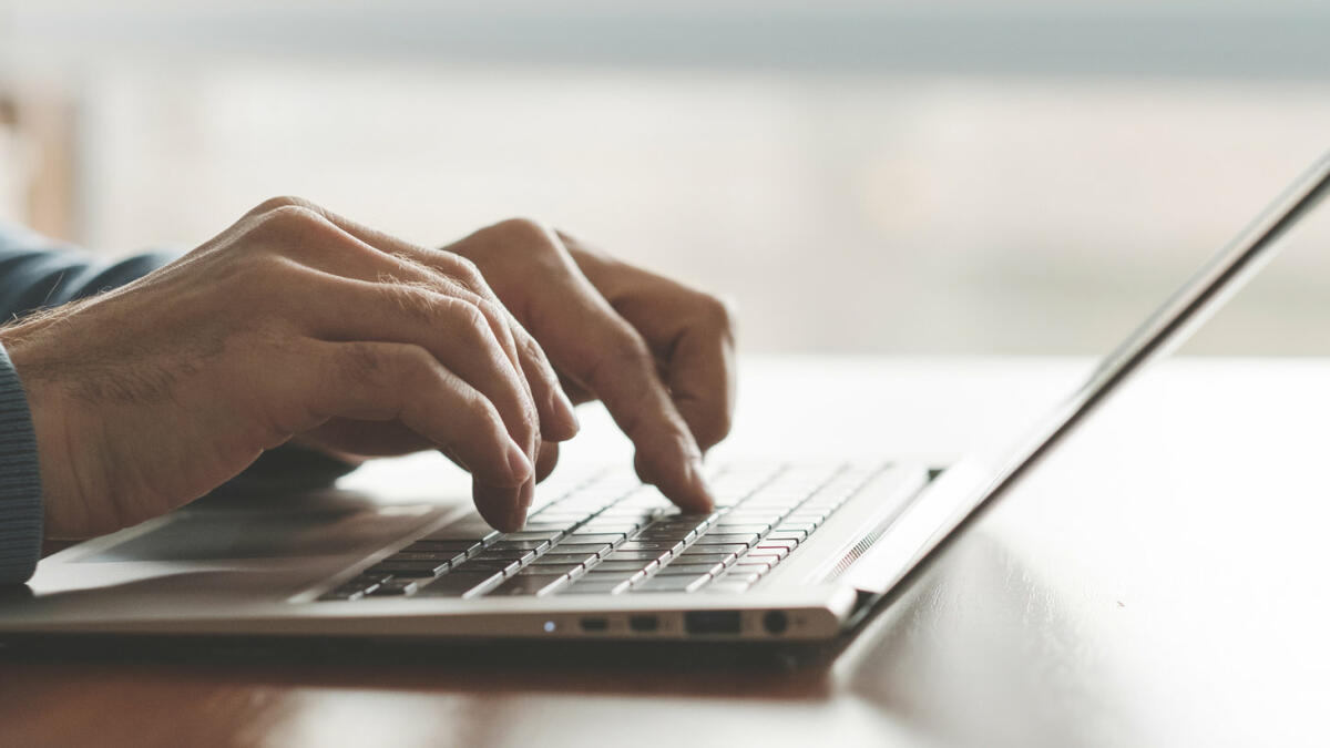 Mann tippt mit seinen Händen auf einem Laptop in der Nahaufnahme © igor_kell / Getty Images