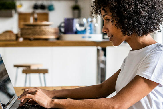 Frau sitzt vor Laptop am Schreibtisch. © Westend61 / Getty Images