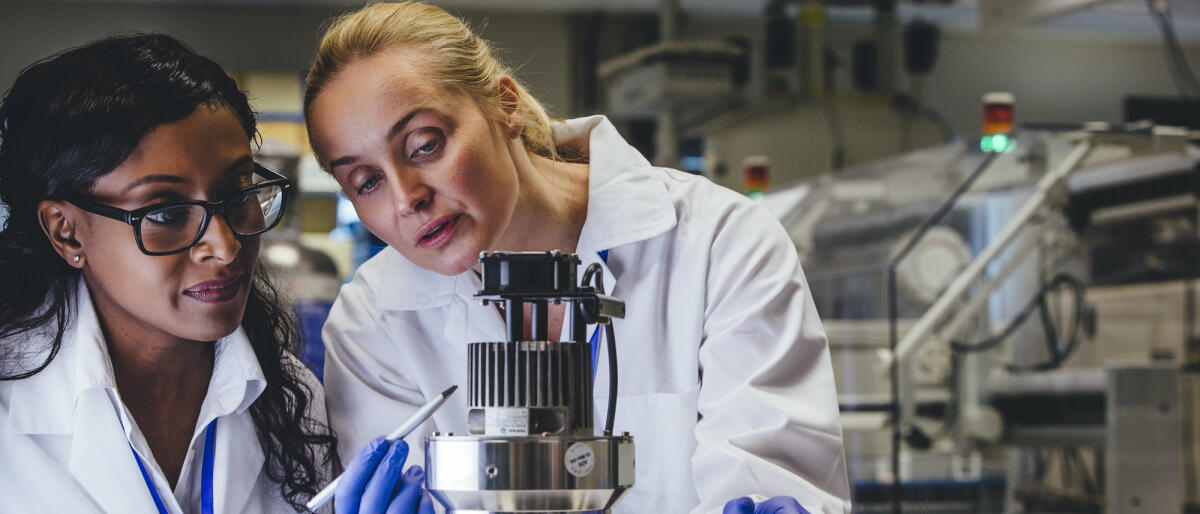 Zwei Frauen stehen im Labor und prüfen gemeinsam ein technisches Gerät © SolStock / Getty Images