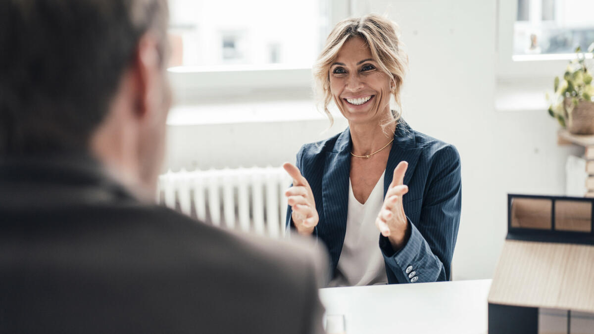 Aufgeregte Bewerberin gestikuliert und spricht mit dem Gegenüber im Büro © Westend61 / Getty Images