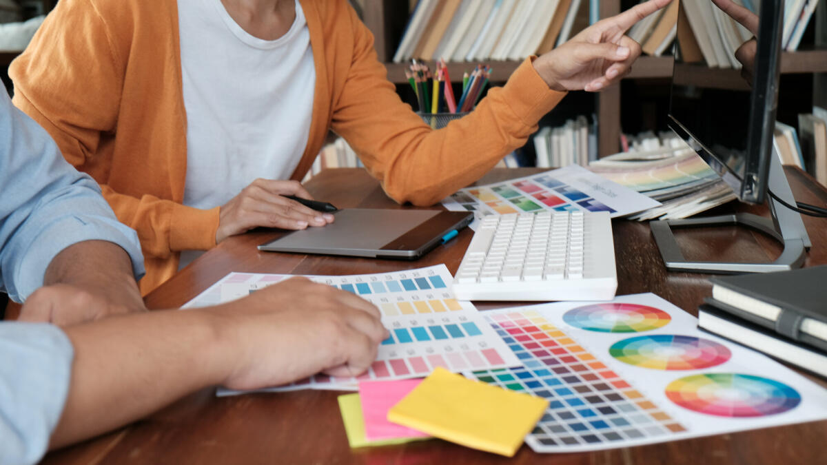 Grafikdesigner, der an einem digitalen Tablet arbeitet. Künstlerzeichnung auf Grafiktabletts und Farbmustermustern. © Dacharlie/ Getty Images