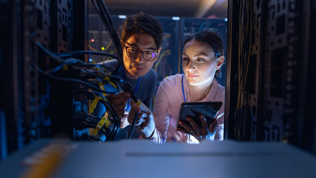 Diverse Ingenieure mit digitalem Tablet inspizieren den Server im Computer-Serverraum. Datenbankserver-Management- und Wartungskonzept. © Wavebreakmedia/ Getty Images